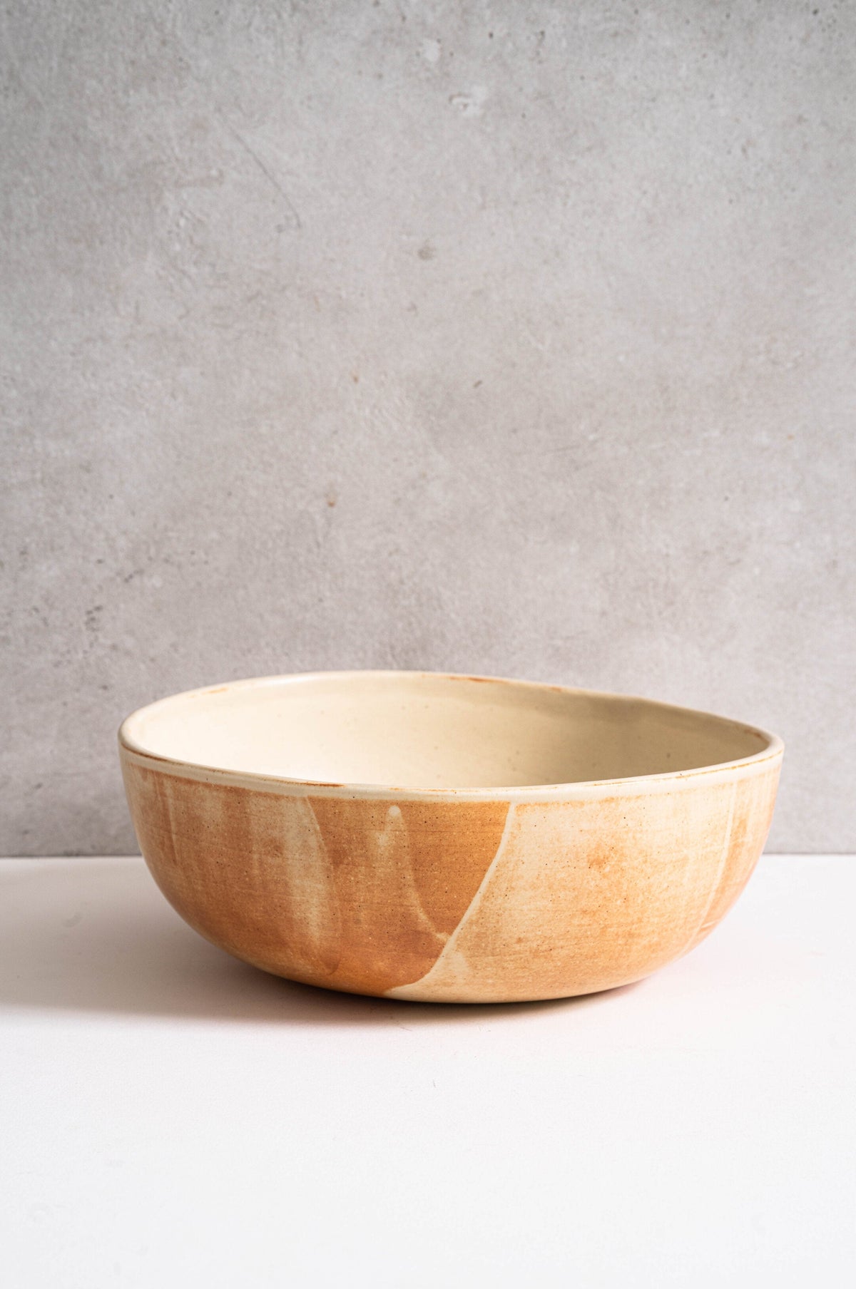 Beige matte stoneware salad serving bowl with unique reactive glaze and rust color strokes