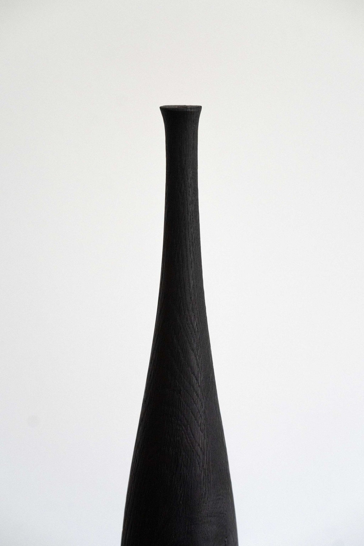 Tall charred wood vase with sharp shoulders and long neck handcrafted from oakwood