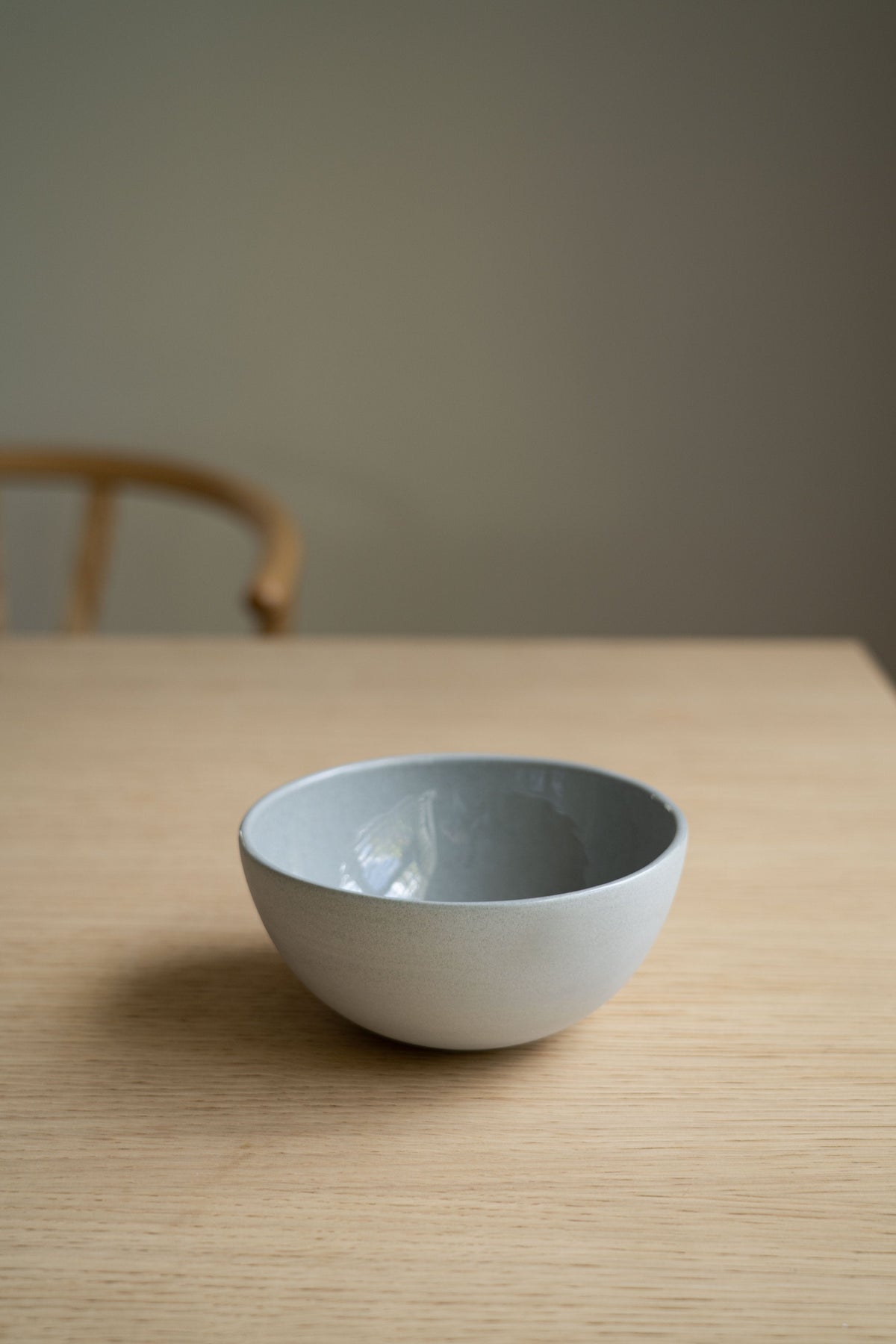 Handmade porcelain bowl in gray sky color with shiny glaze and smooth polished exterior