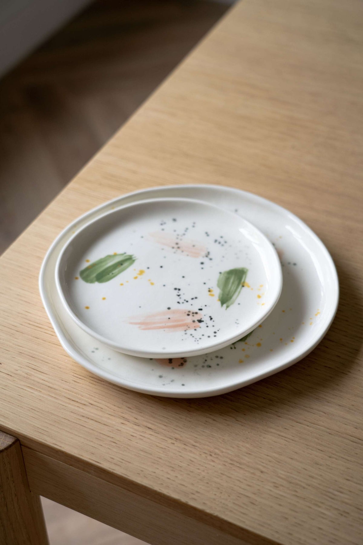 Off-white handmade porcelain dinner plate with hand-painted strokes, shiny glaze, and simple elegant design