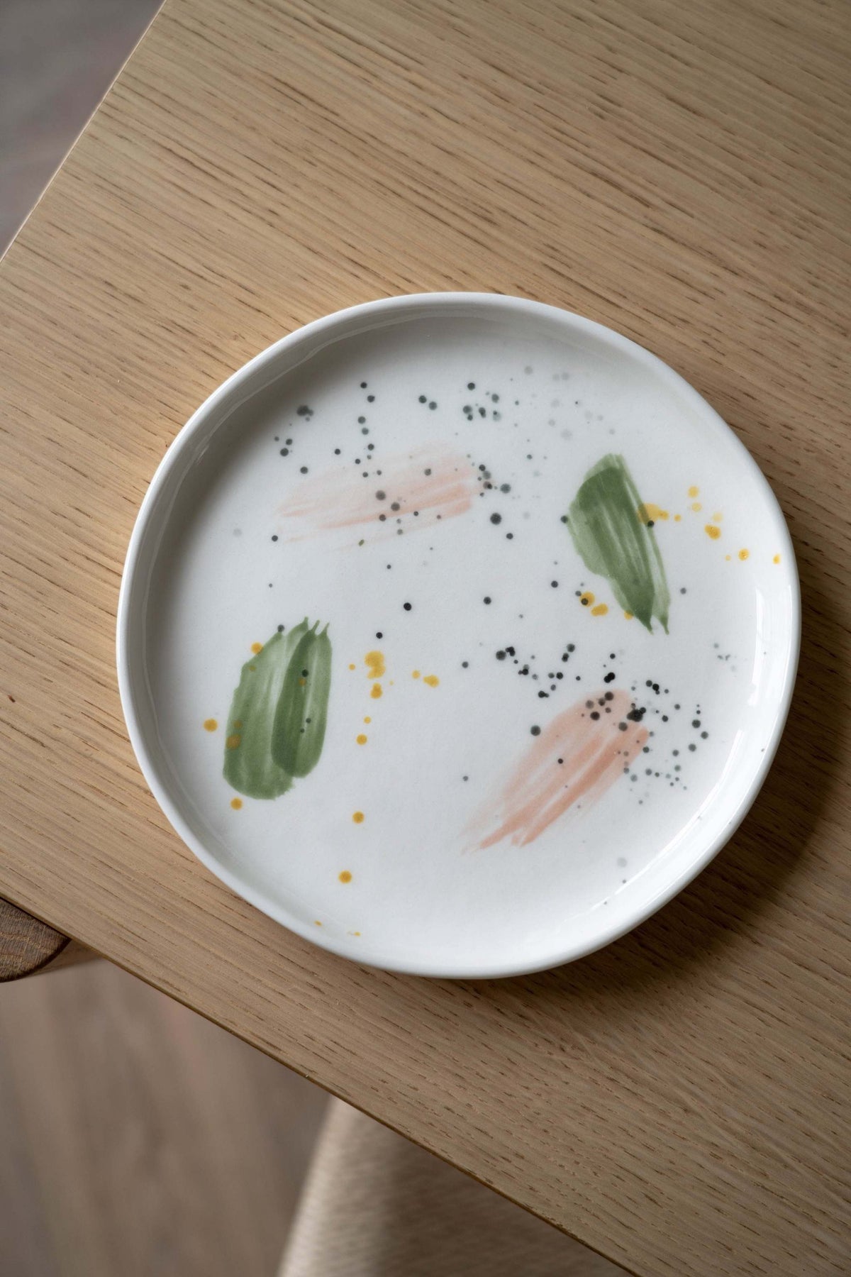 Off-white handmade porcelain dinner plate with hand-painted strokes, glossy finish, and simple elegant design