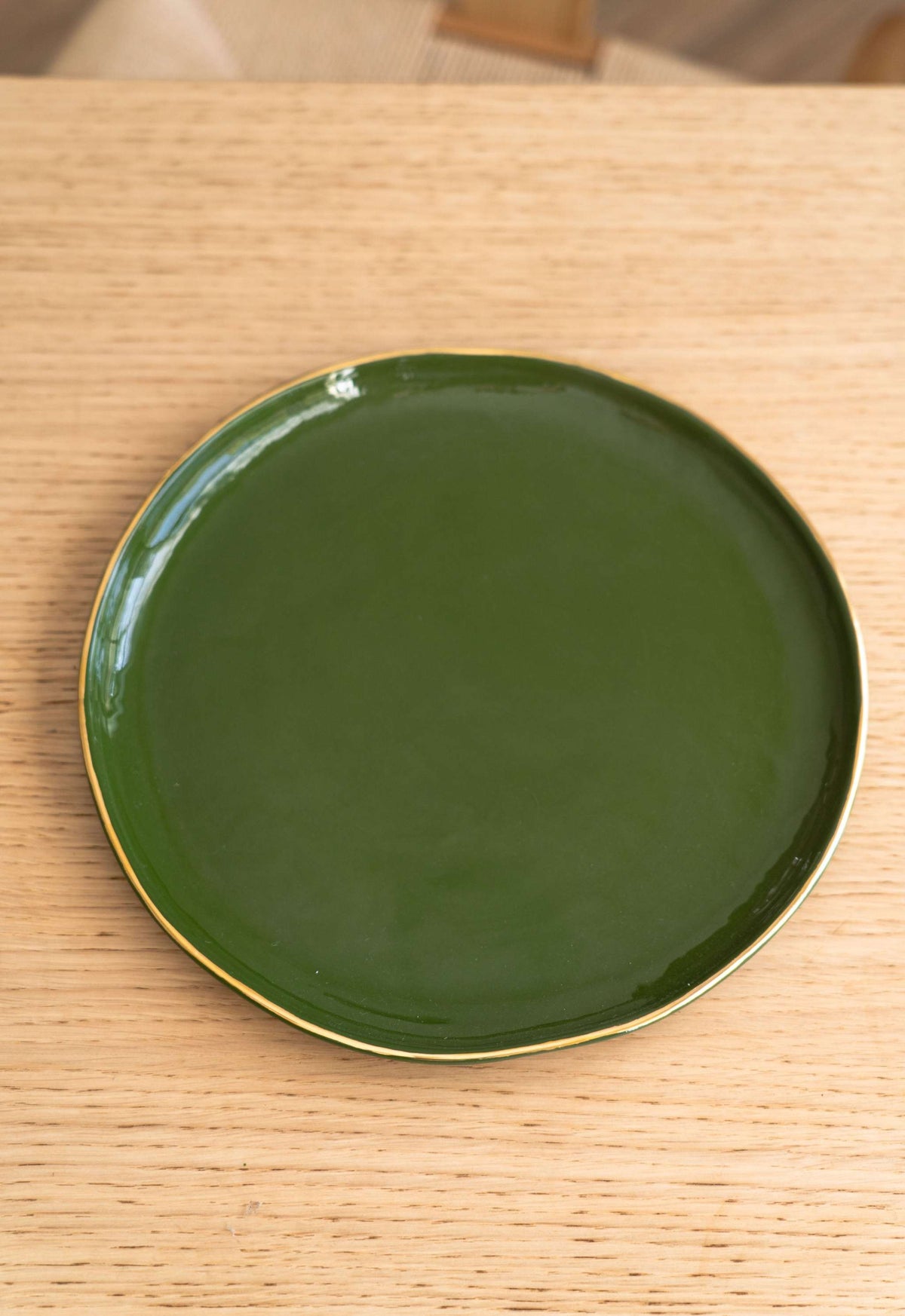 Handmade porcelain dinner plate with gold rim and green finish, elegant and glossy.