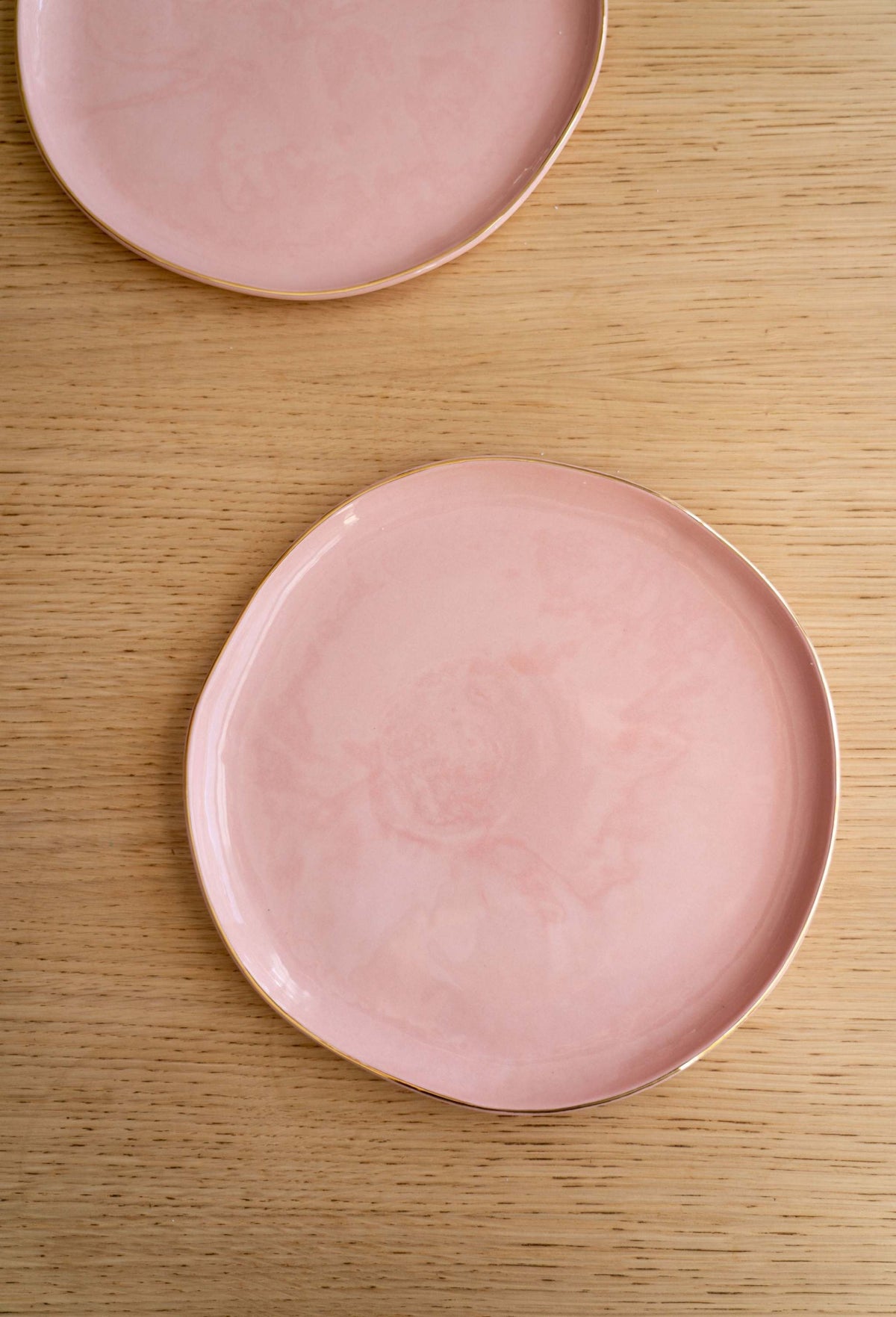 Handmade porcelain dinner plates in powder pink with gold rim, glossy finish, and polished exterior