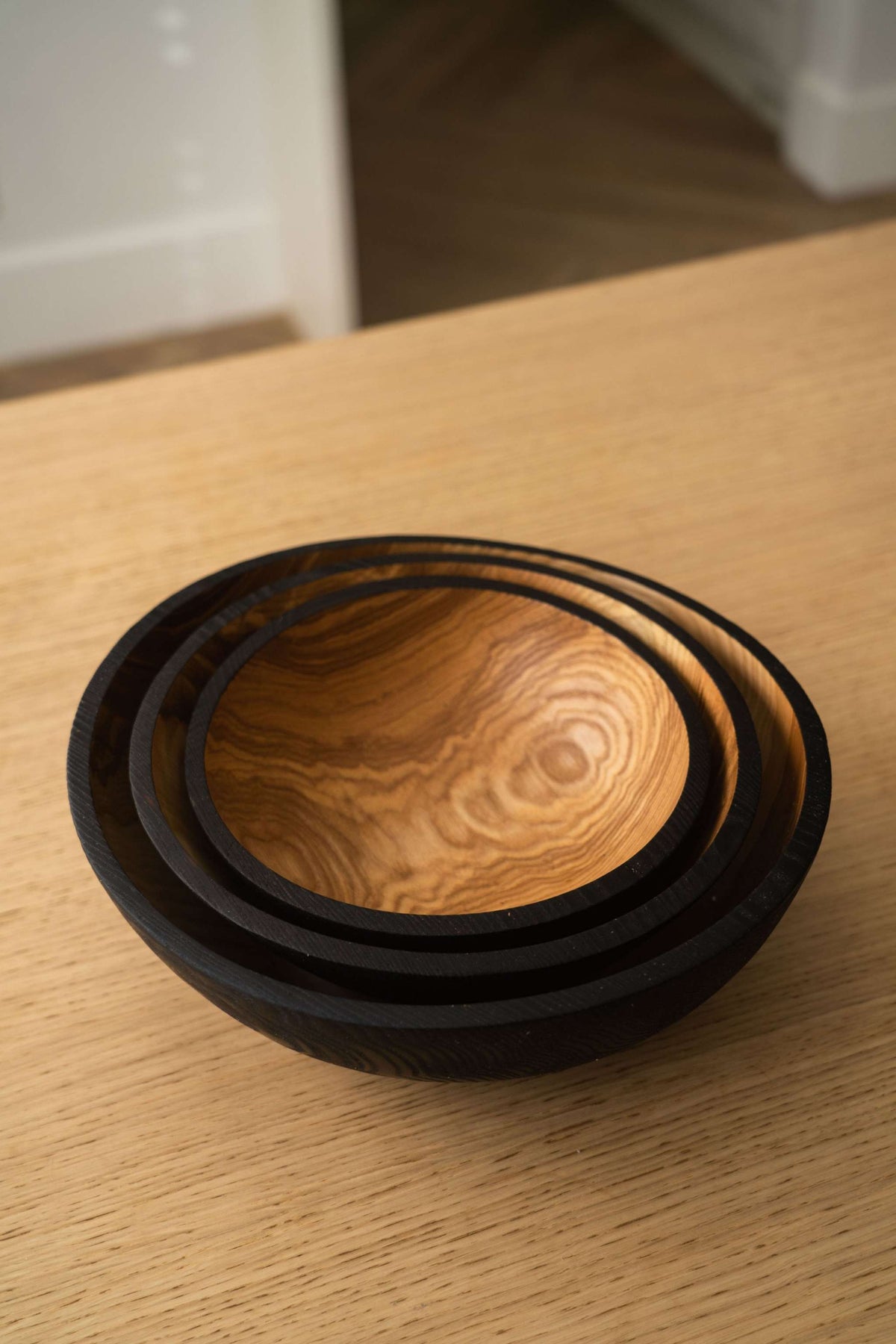 Nesting Bowl Set of three nested ashwood bowls, with black charred rims and richly swirling natural wood grain inside.