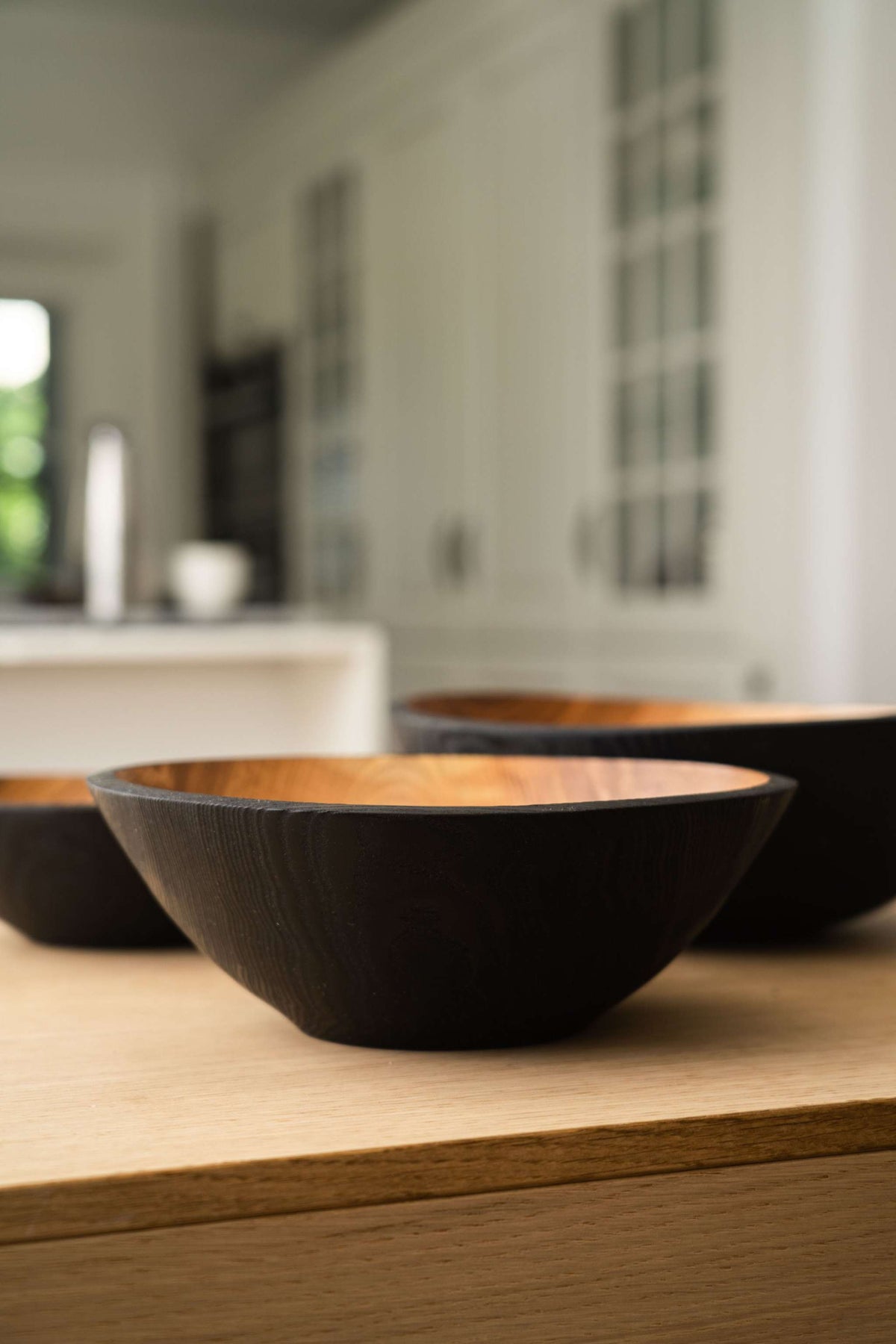 Nesting Bowl Set of three dark charred wood bowls with warm natural interiors and visible grain, nested together