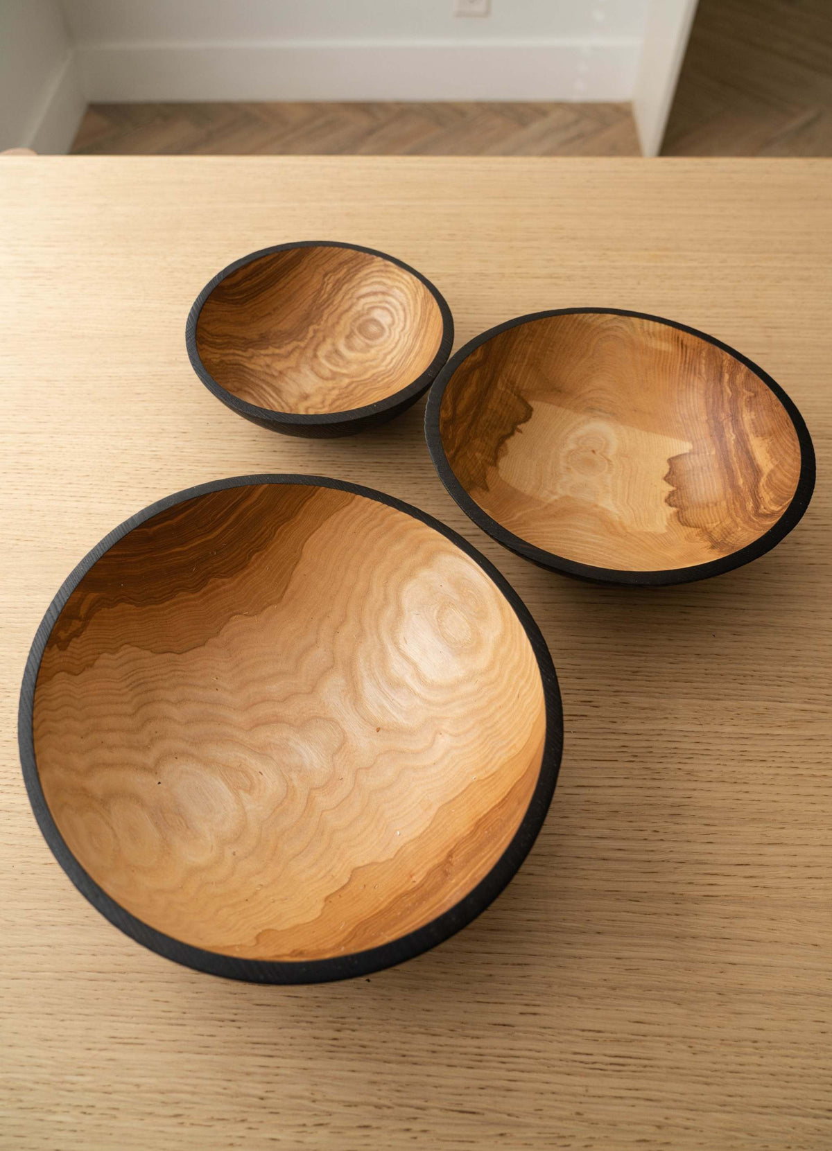 Nesting Bowl Set of three hand-carved ashwood bowls with natural swirling grain and contrasting charred black rims.