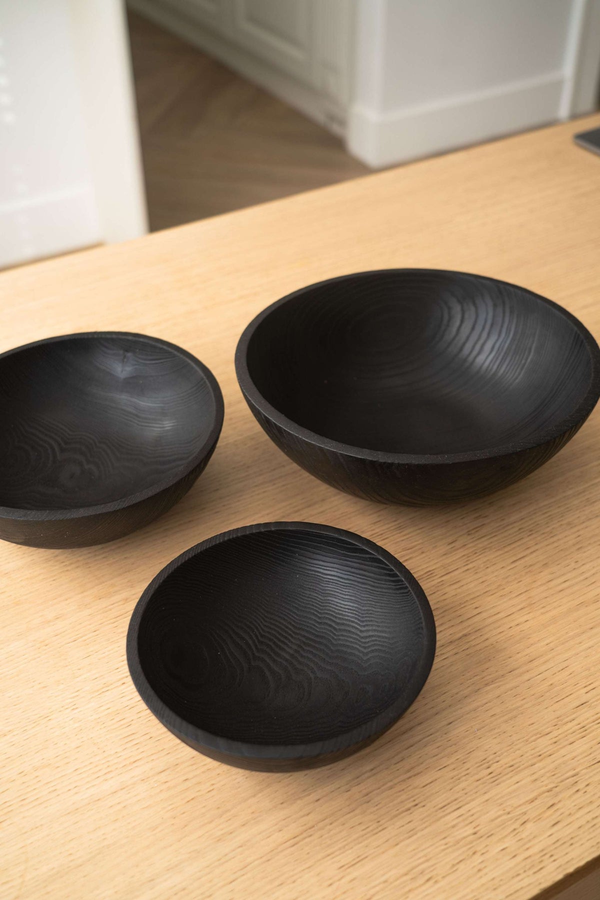 Hand Carved Charred Wooden Salad Bowl Set with three black bowls, smooth carved wood grain and rounded rims.