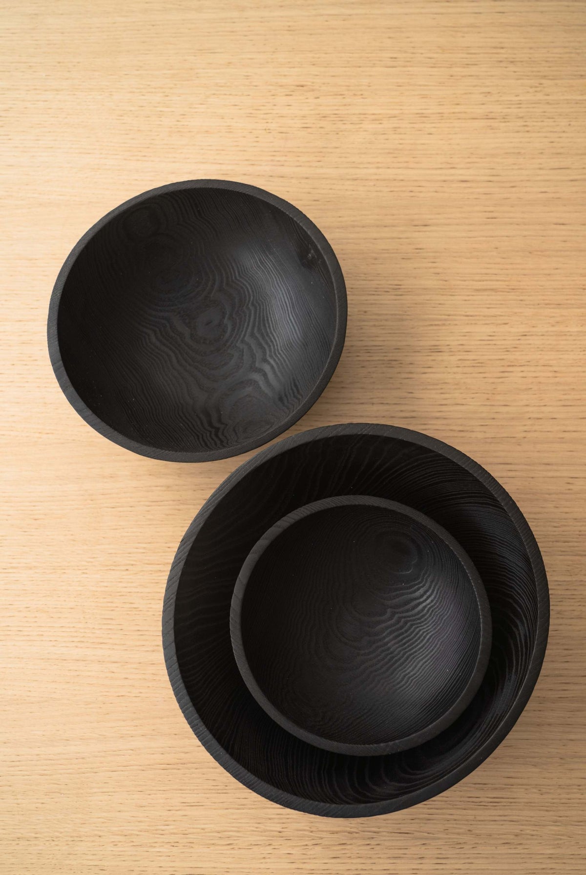 Hand Carved Charred Wooden Salad Bowl Set in black wood, featuring three nested bowls with carved grain patterns and smooth rims.