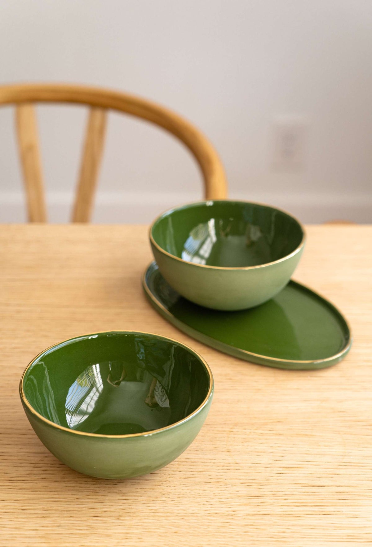 Green porcelain oval serving platter with gold rim and organic edges for elegant dining