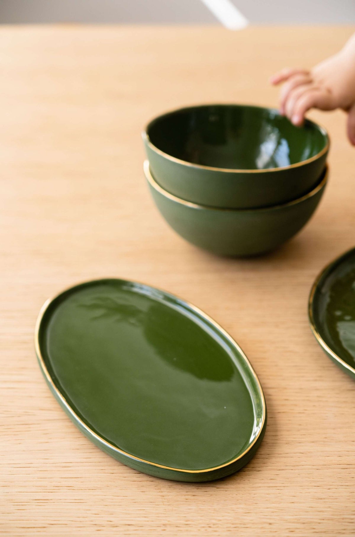 Green porcelain oval serving platter with gold rim and organic round edges