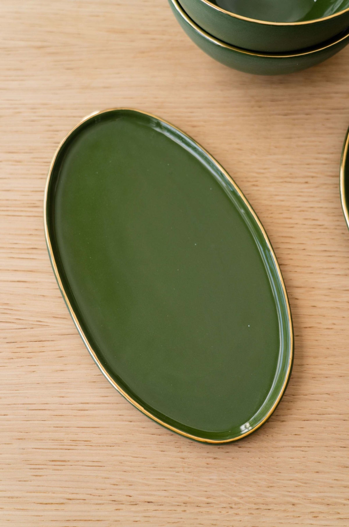 Green porcelain oval serving platter with gold rim and organic edges
