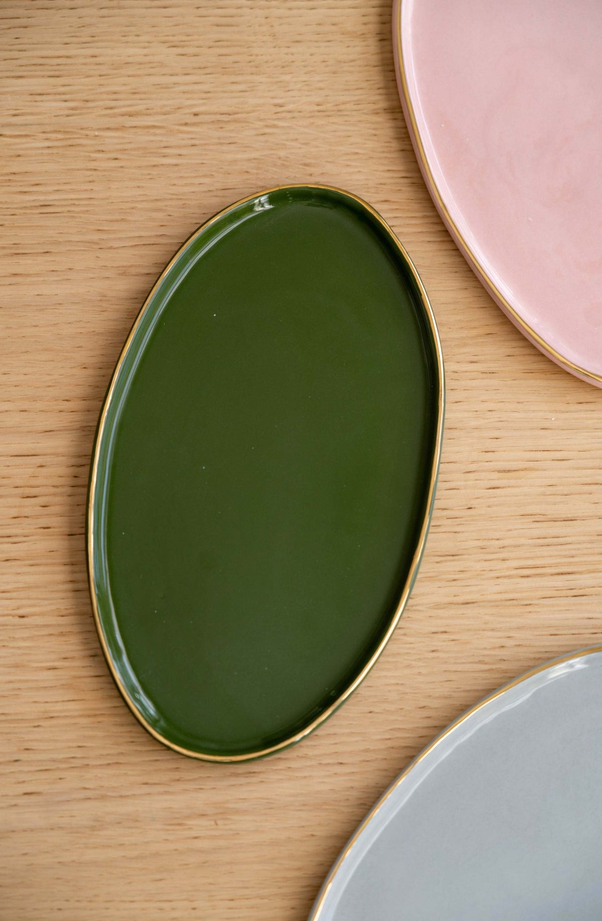 Green porcelain oval serving platter with gold rim and organic edges for everyday and special occasions