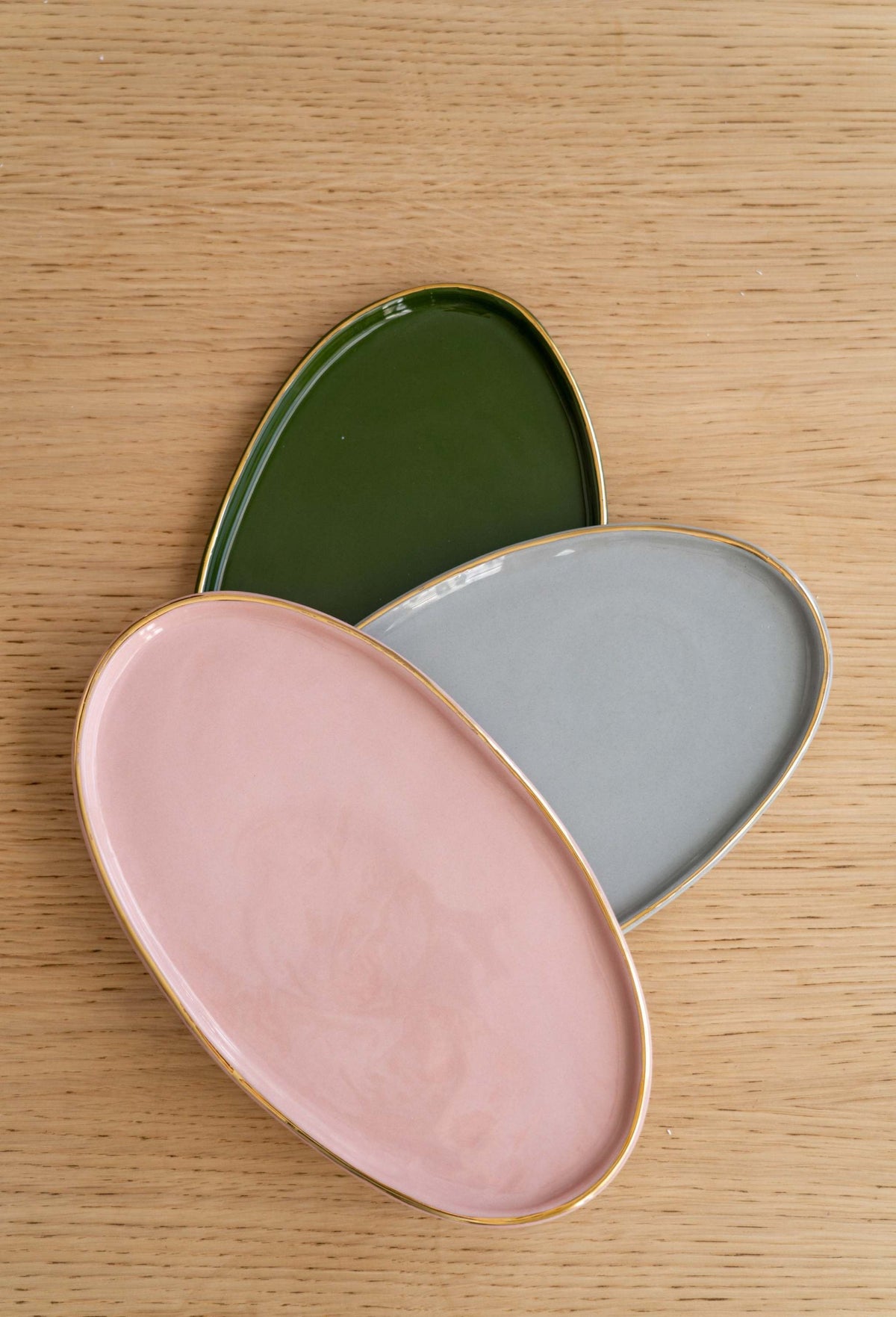 Handmade oval porcelain serving platter in powder pink with gold rim and organic edges