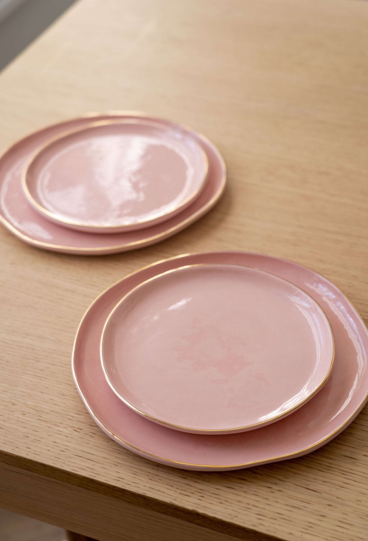 Handmade porcelain dinner plates powder pink with gold rim set on table