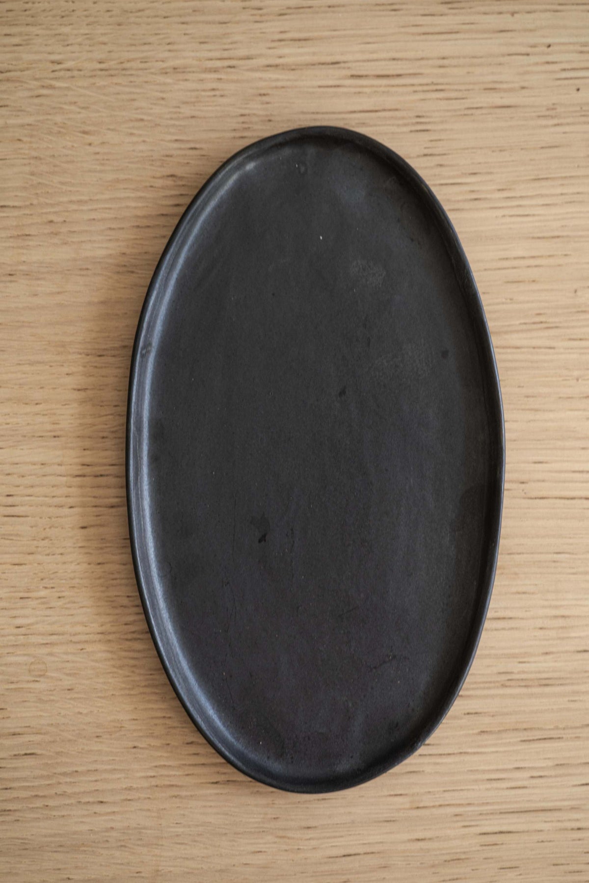 Handmade black matte stoneware oval serving platter with organic edges and reactive glaze, food-safe and lead-free, made in Ukraine