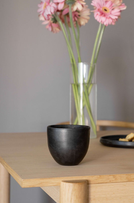 Hand made black matte stoneware coffee cup with organic edges and reactive glaze