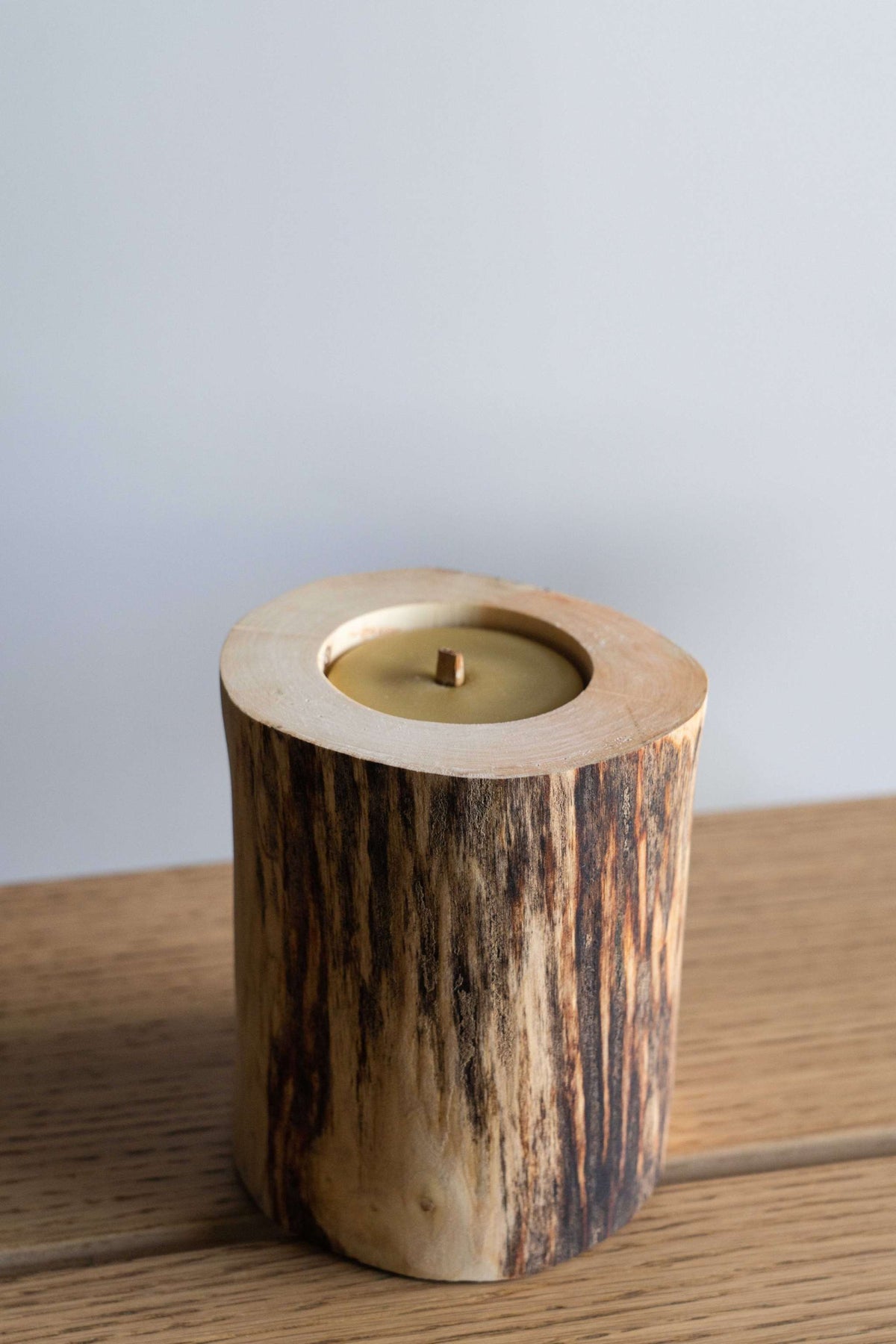 Hand Craft Ubud Wooden Candle in a natural wood holder with charred dark grain, pale rim, and beeswax insert.