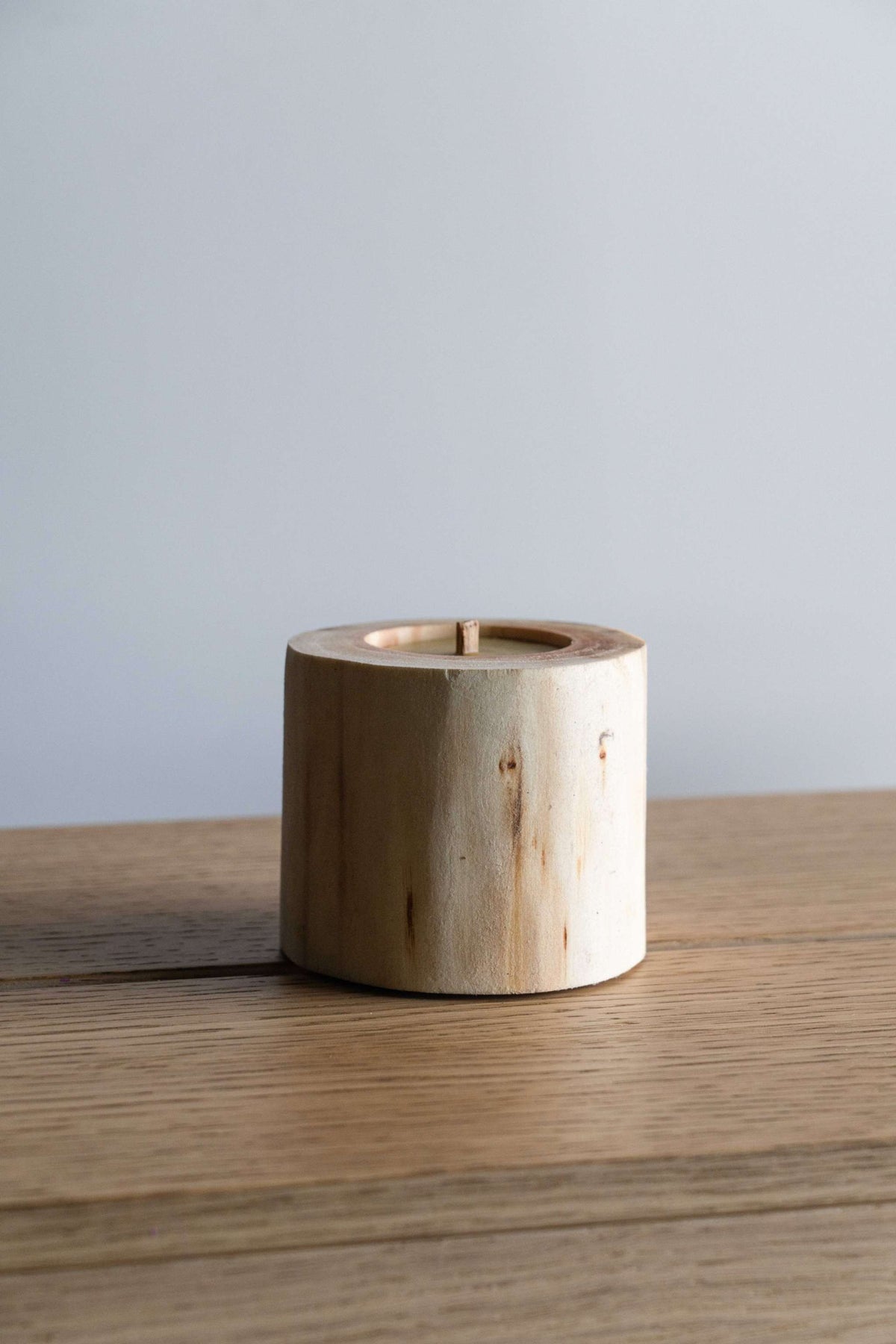 Hand Craft Ubud Wooden Candle in a natural pale wood holder, cylindrical with visible grain and a central wick.