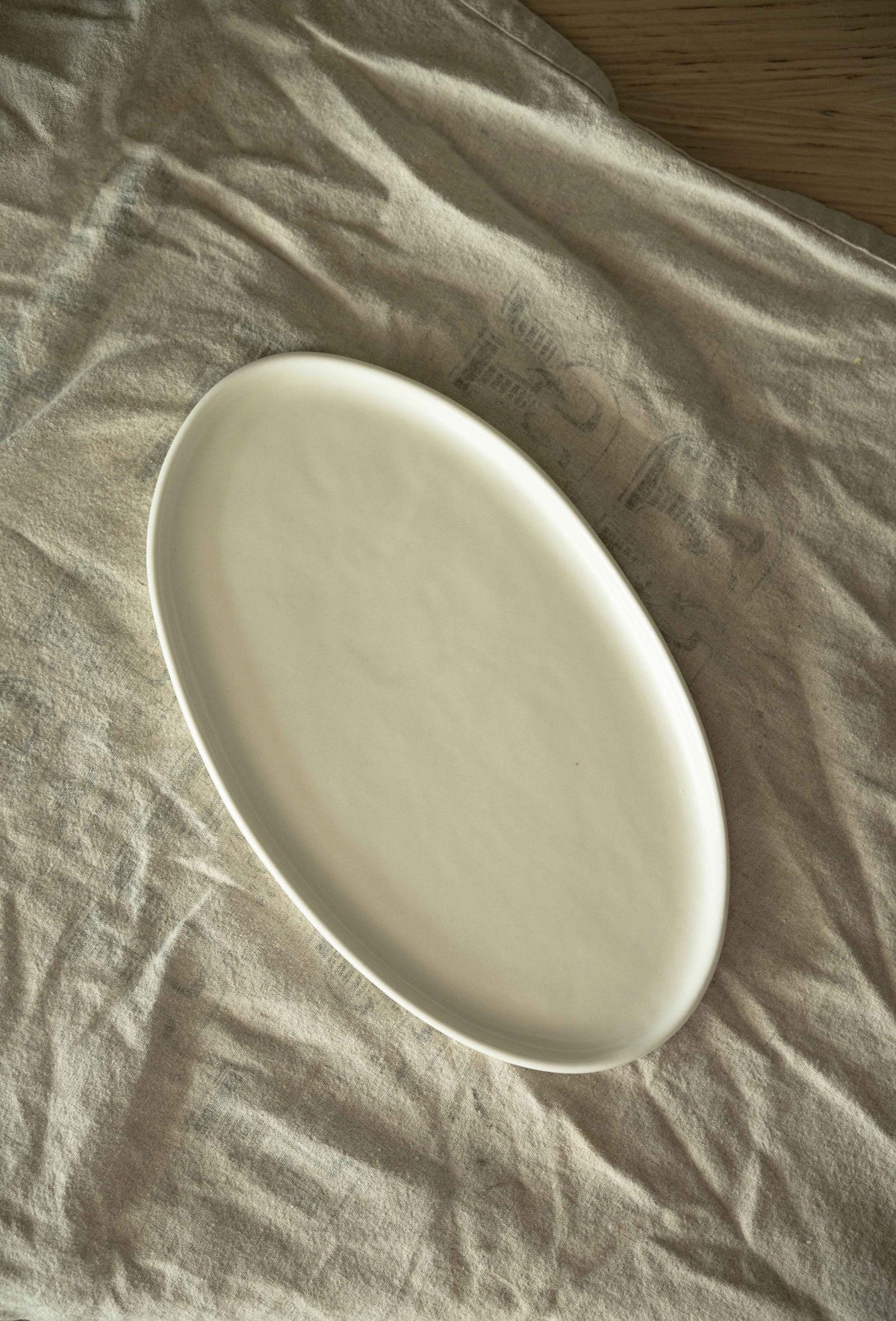 White matte stoneware oval serving platter with organic edges and reactive glaze, handmade in Ukraine