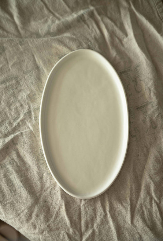 Handmade white matte stoneware oval serving platter with organic edges and reactive glaze, dishwasher and microwave safe