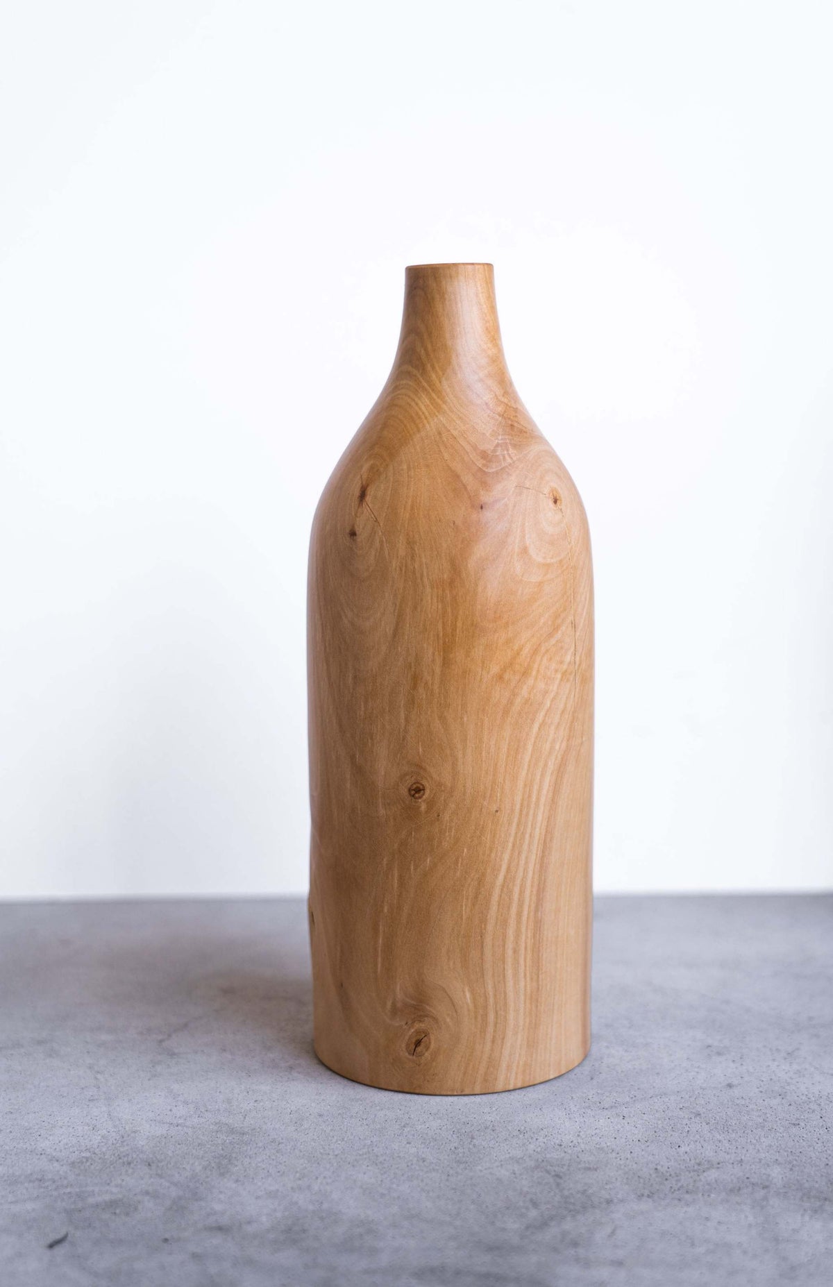 Handcarved pear wood bottle-shaped vase with natural grain and smooth finish, elegant home decor piece