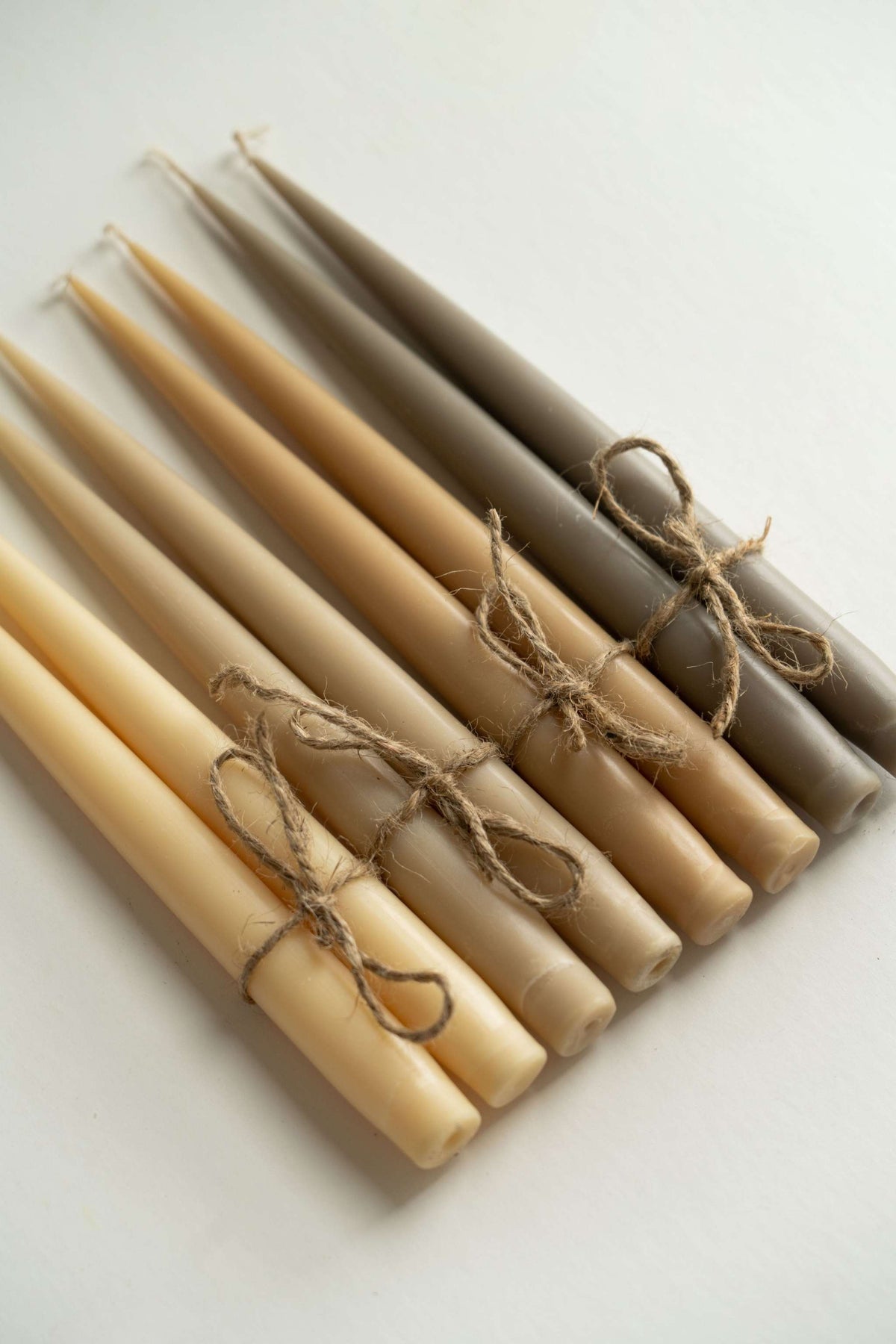 Set of narrow taper candles in glass holders, handmade from soy wax with cotton wicks, available in four colors.