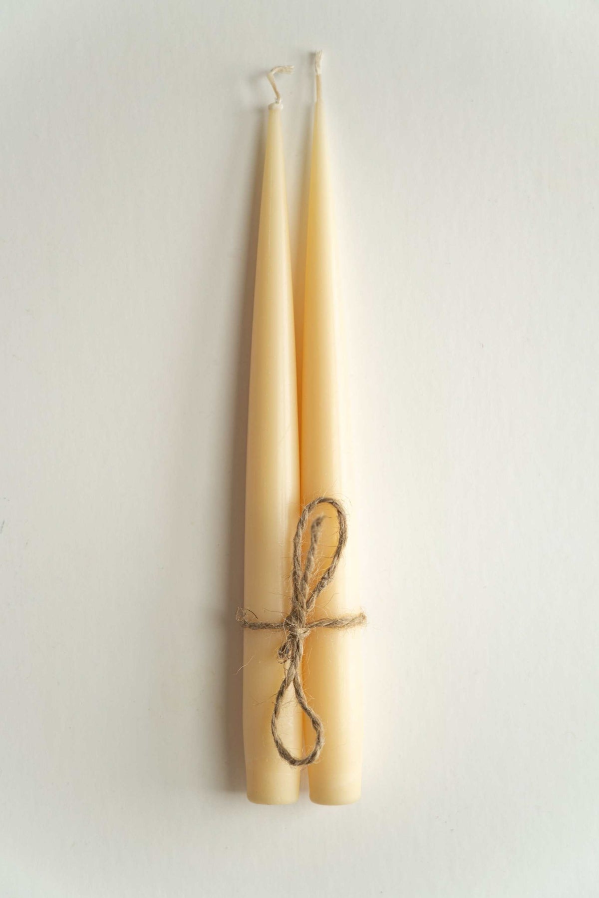 Set of handmade narrow taper candles in assorted colors with cotton wicks in glass holders