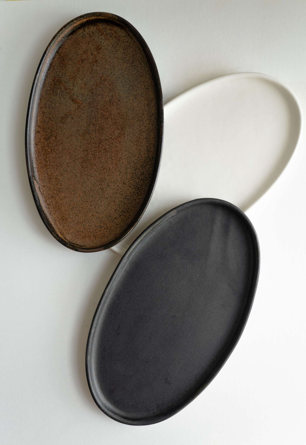 Handmade black matte stoneware oval serving platter with organic edges and unique reactive glaze swirl