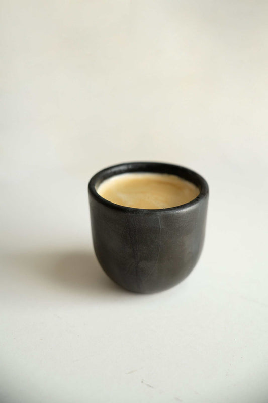 Handmade black stoneware espresso cup with reactive glaze and organic edges