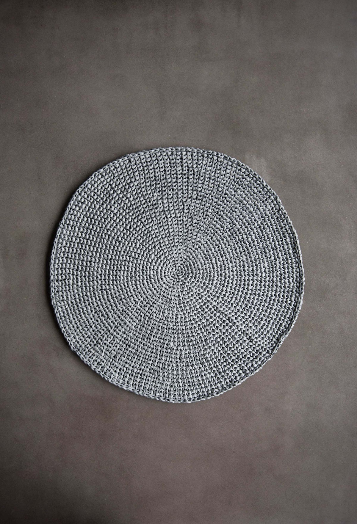 Round Raffia Placemats in silver gray raffia, hand-crocheted with a tightly coiled circular weave and scalloped edge.