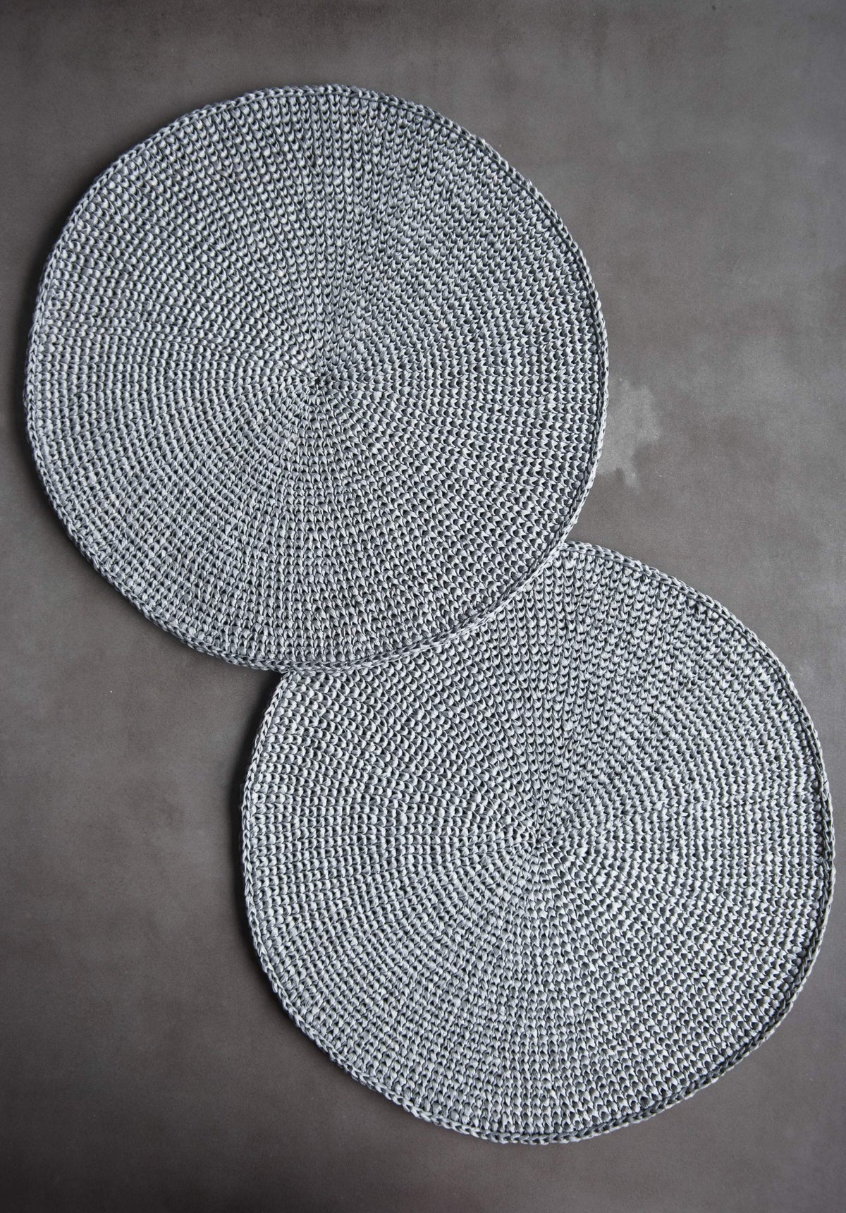Round Raffia Placemats in silver-gray woven raffia, hand-crocheted into round shapes with a tight spiral stitch pattern.