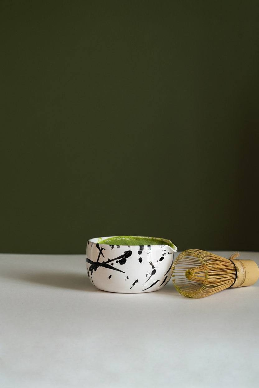 Handmade Matcha Bowl, a white glazed stoneware cup with bold black brushstroke splashes and a green rim.