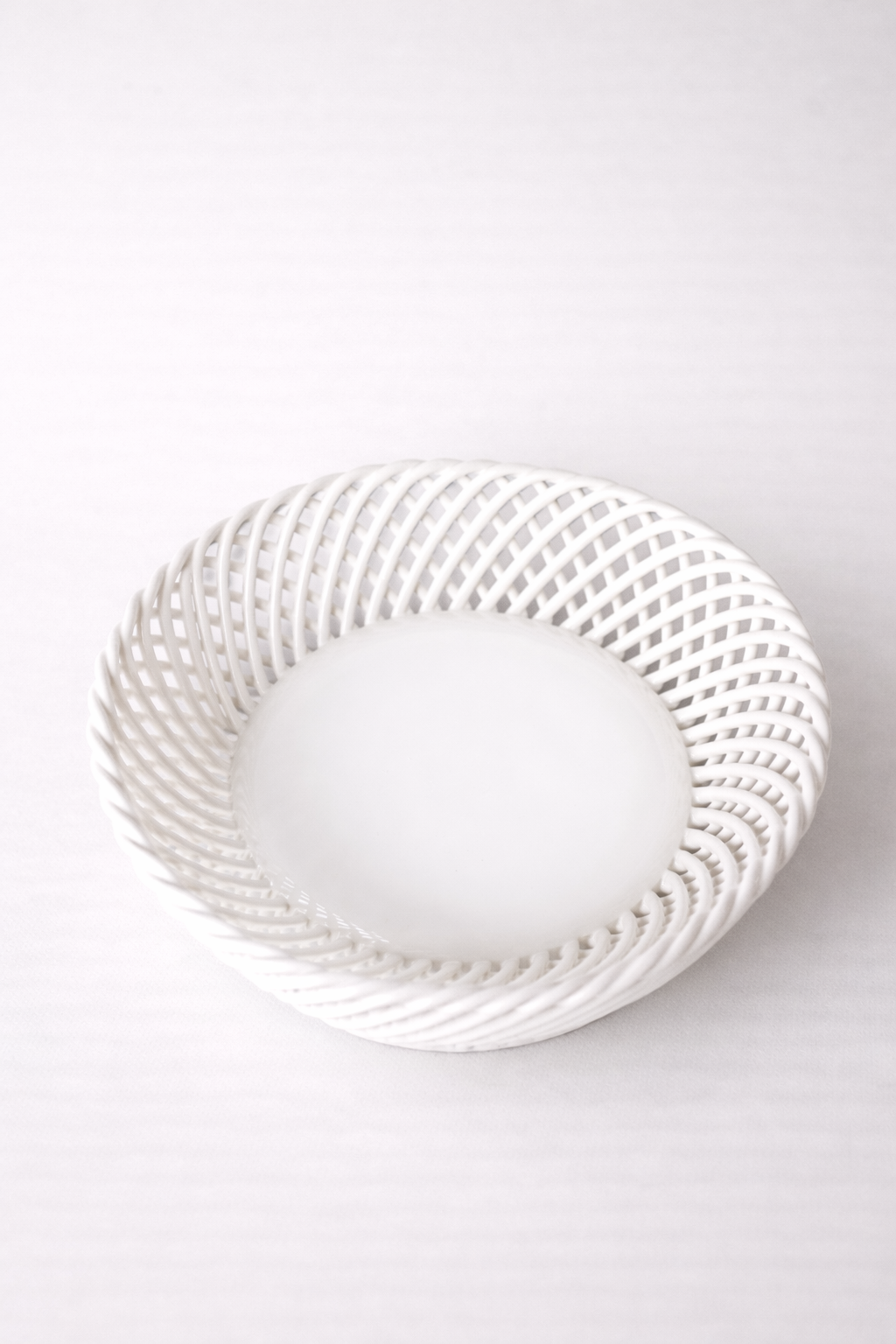 Ceramic Round Hand-Woven Basket in glossy white porcelain, with an open interlaced weave and rounded shape.