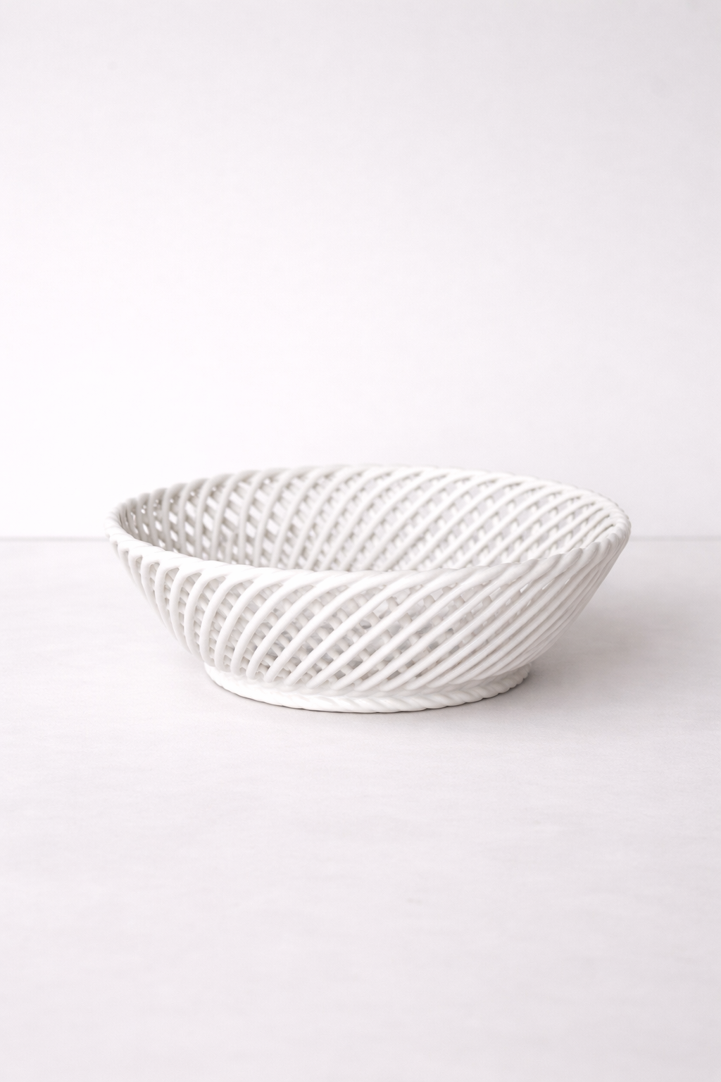 Ceramic Round Hand-Woven Basket in glossy white porcelain, with an airy interlaced design and oval-shaped rim.