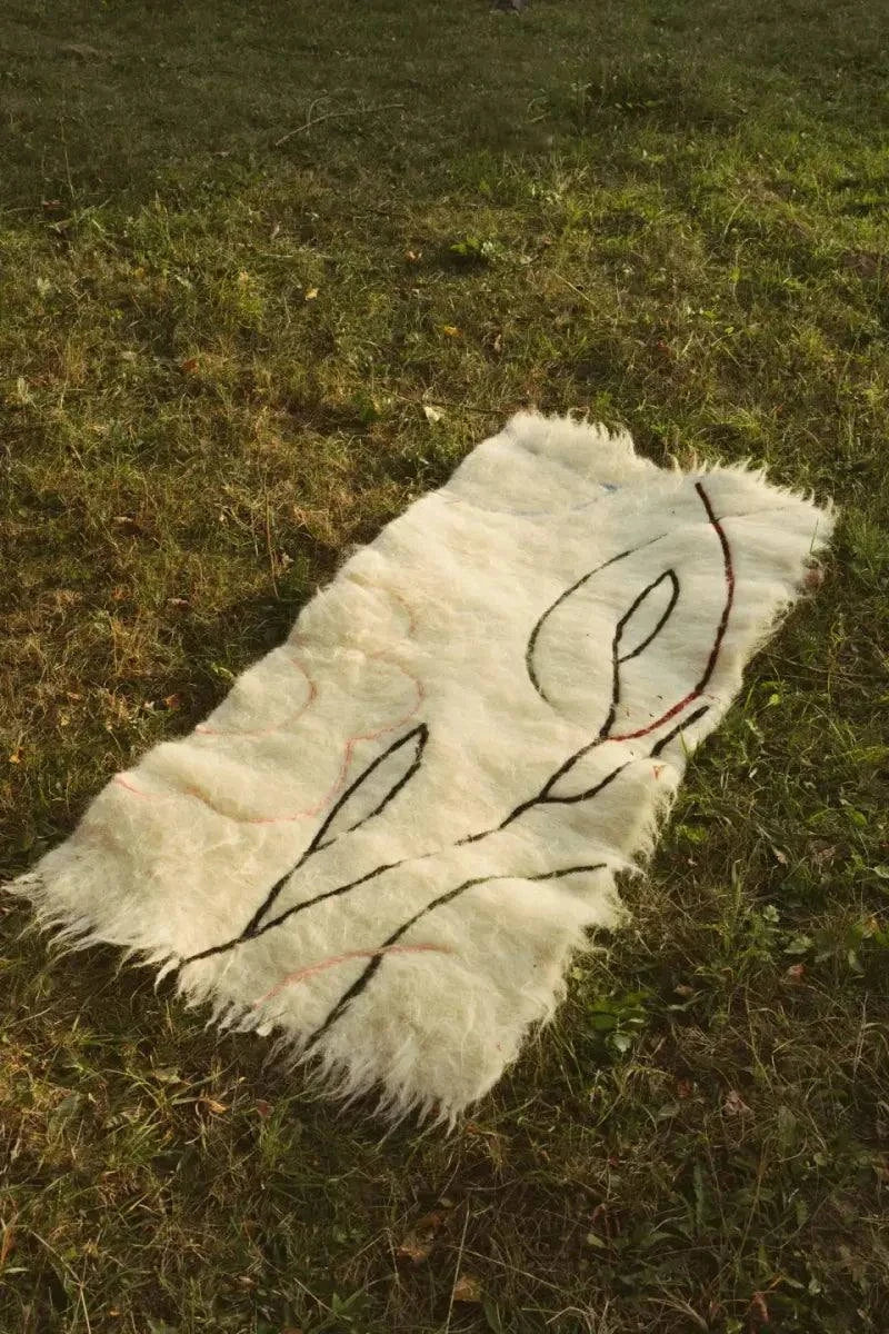 Handwoven wool runner rug with creamy brushed texture and delicate floral outlines on cotton base