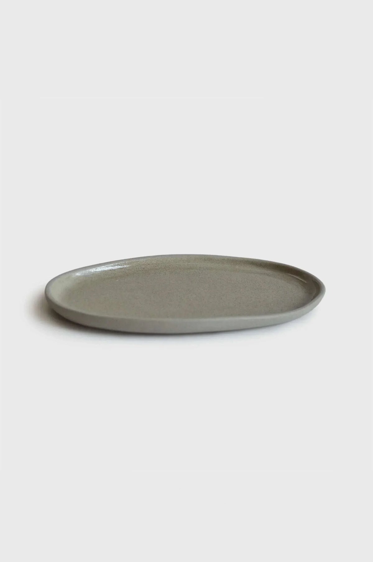Handmade Stoneware serving platter in muted gray with a smooth glossy center, gently raised rim, and rounded oval shape.