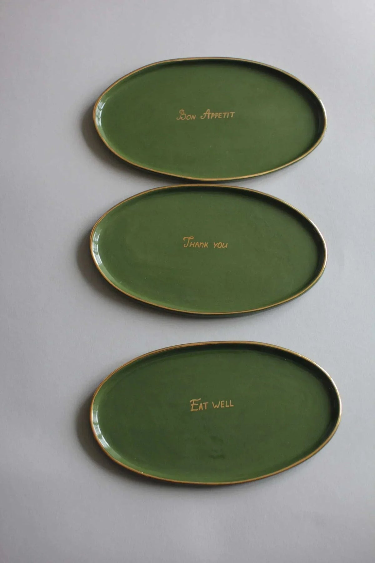 Personalized Wedding Platter set of three oval green ceramic trays with gold rims and small gold lettering inside each dish.