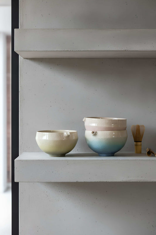 Ceramic Matcha Bowl, cream stoneware with a pale green glaze and pouring spout, beside a blue-gradient cup.
