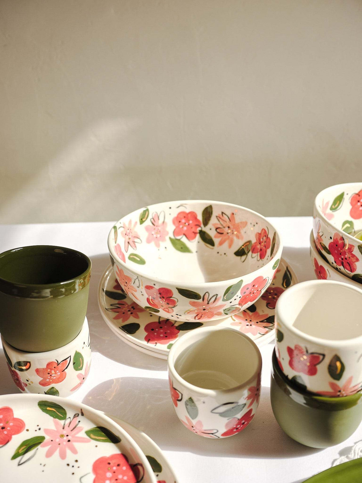 Hand-Painted Floral Coffee Cup in ivory porcelain with pink and red flowers, green leaves, and a dark green handle.