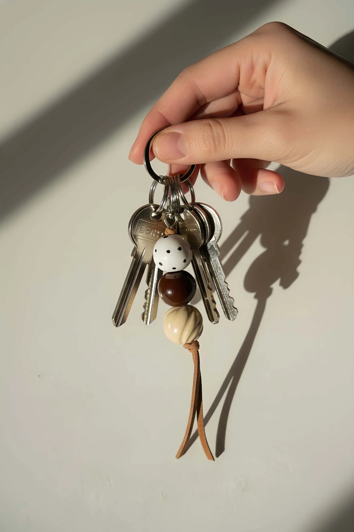 Ceramic Beaded Keychain with white dotted, dark brown and cream beads, silver-tone keys and a brown leather cord.